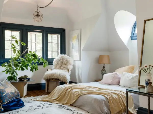 Cozy bedroom with a fluffy chair, yellow throw, and plants. Learn how to pick bedroom furniture for a stylish, inviting space.